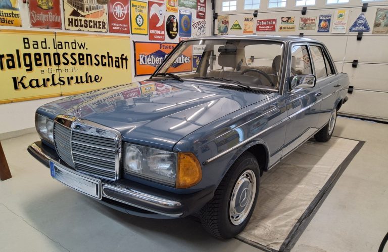 Blauer Mercedes-Benz der 80er Jahre in einer Ausstellungsraum mit historischen Werbeschildern.