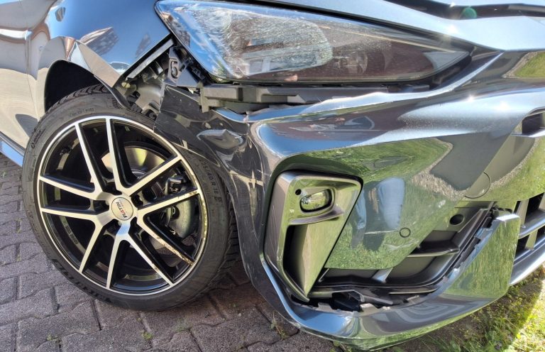 Beschädigtes Auto mit beschädigtem Kotflügel und zerkratztem Reifen.